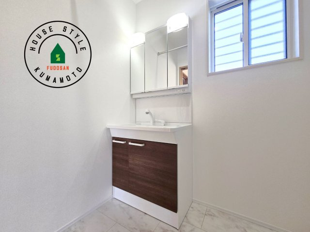 熊本市西区中原町第1-4棟（1号棟）の内観：施工例|毎日使うものだから清潔な空間を保ちたい水回り。洗面にはそんな願いを解消させてくれる収納アイデアが満載です。三面鏡の裏側にはキャビネットが現れ小物から背の高い物まで収納できます。