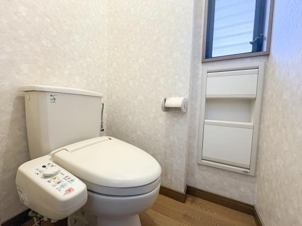 荏隈　中古のトイレ|温水洗浄便座が備わっており快適にご利用いただけます。窓付きで換気も考慮された空間です。壁と床のカラーが落ち着いた雰囲気を演出しています。収納も設けられ使い勝手に配慮されています。
