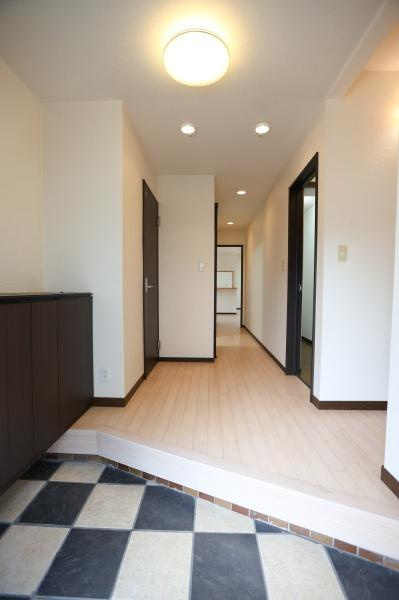 葛木　中古の玄関|玄関は明るい照明とシンプルなデザインですっきりとした印象です。ゆるやかな段差があり使い勝手の良いスペースです。収納がしっかりと設けられており整理整頓がしやすい玄関です。