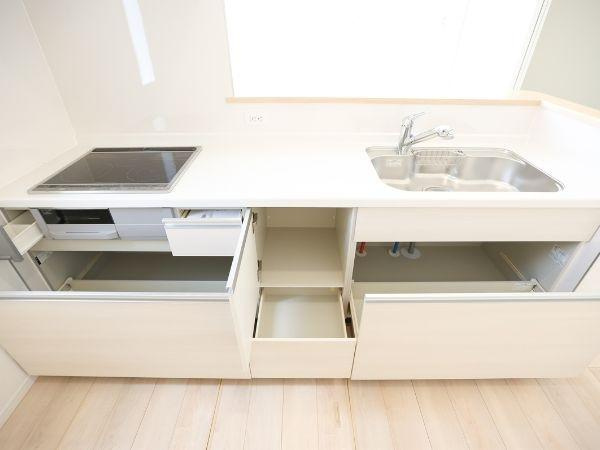 挾間町下市第1-4号棟のキッチン|明るく清潔感のあるキッチンです。広々としたワークトップが特徴です。大きなシンクとIHクッキングヒーターが設置されています。収納スペースも豊富に設けられています。