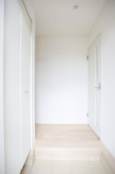 挾間町下市第1-4号棟の玄関|シンプルで明るい印象の玄関です。白を基調とした空間が爽やかさを演出しています。段差があり靴の脱ぎ履きがしやすい設計です。収納スペースも備えられています。