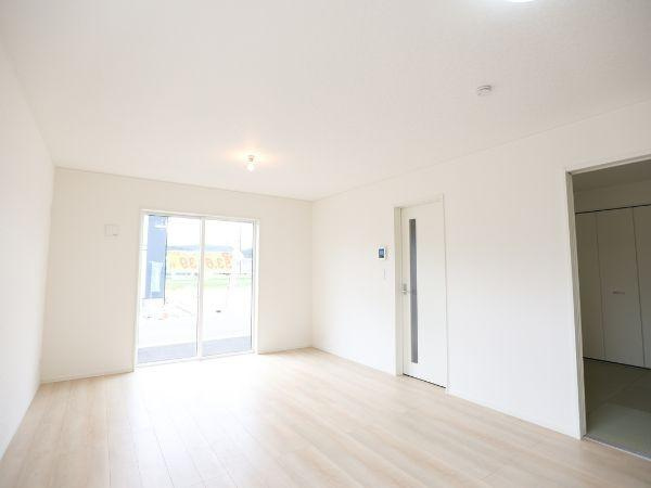 挾間町下市第1-4号棟の居間・リビング|明るい光が差し込むリビングはナチュラルなフローリングが印象的です。シンプルな壁面が空間を広く見せます。大きな窓が開放感を演出しています。隣接した扉や収納スペースも使い勝手が良さそうです。