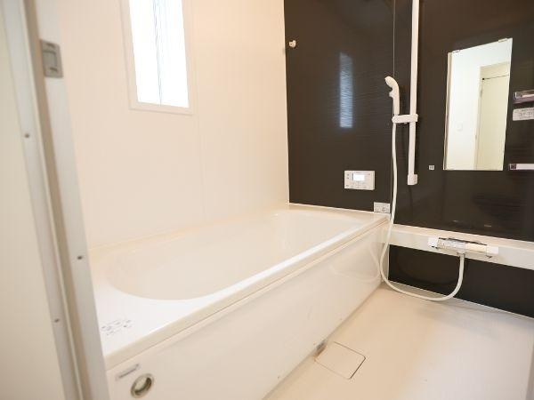 挾間町下市第1-3号棟の浴室|清潔感のあるバスルームです。白を基調とした空間に黒いアクセントパネルが上品な印象を与えます。ミラーやシャワーの配置も使いやすく整っています。窓があり自然光が入りやすい点もポイントです。