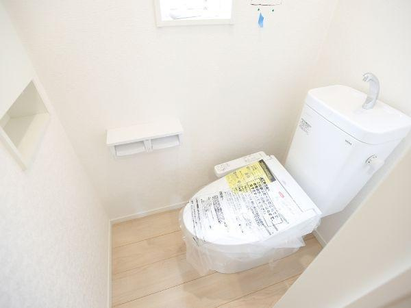 挾間町下市第1-3号棟のトイレ|明るい色合いの床と壁で清潔感が感じられるトイレです。シンプルなデザインでお手入れがしやすそうです。窓があり換気にも配慮されています。