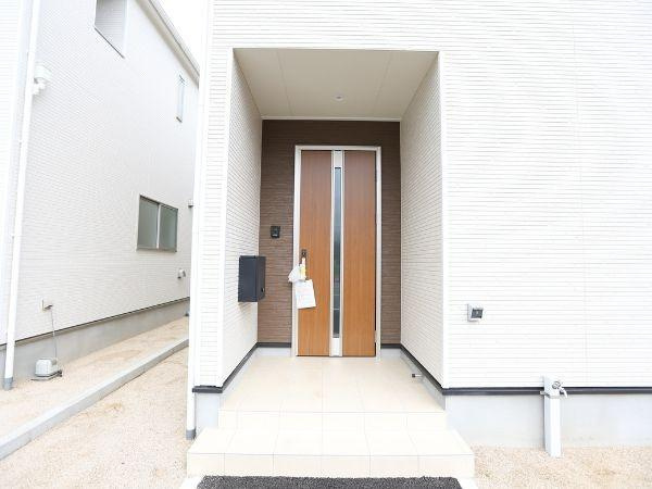 挾間町下市第1-3号棟の玄関|広々とした玄関で開放感があります。玄関ドアのデザインがシンプルでスタイリッシュです。屋根付きのポーチが雨の日も安心です。白を基調とした外壁が明るい印象を与えます。