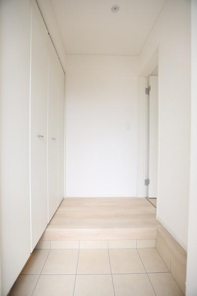 挾間町下市第1-3号棟の玄関|シンプルですっきりとした玄関です。白を基調とした内装が空間全体に明るさをもたらしています。収納スペースが充実しており整理整頓しやすい設計です。段差があり空間にメリハリを感じられます。