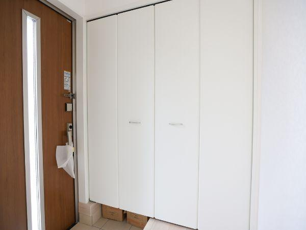 挾間町下市第1-3号棟の玄関|玄関には大きな収納スペースが備わっており整理整頓に便利です。すっきりとした白い扉が空間を広く見せます。木目調のドアがアクセントになっています。採光窓付きで明るい雰囲気に仕上がっています。