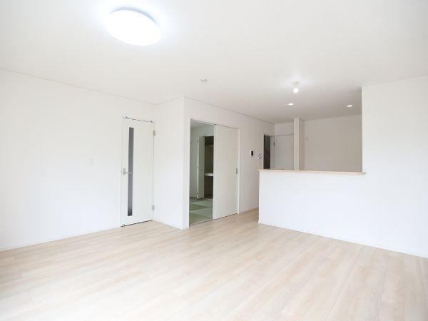 挾間町下市第1-3号棟の居間・リビング|リビングは明るいフローリングと白を基調とした壁が調和し清潔感のある印象です。広々とした空間でさまざまなレイアウトが楽しめます。キッチンカウンターとの繋がりもあり生活動線がスムーズです。