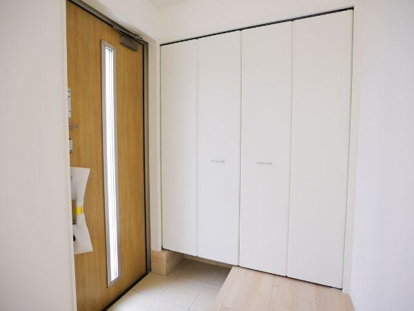 挾間町下市第1-2号棟の玄関|玄関は明るい木目調の扉と白を基調とした収納スペースが調和してすっきりとした印象です。広々としたスペースがあり使い勝手や整理整頓にも配慮されています。