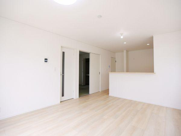 挾間町下市第1-2号棟の居間・リビング|リビングは白を基調とした明るい空間です。広々としたフローリングが印象的です。収納や動線も工夫されています。キッチンとのつながりもあります。開放感のあるリビングです。