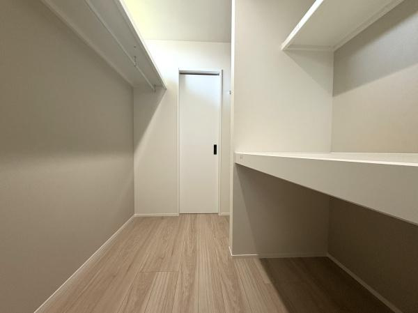 寒田南町二丁目　中古の独立洗面台|こちらのファミリークローゼットは、非常に広々としており、収納力に優れたスペースです。部屋の中央には大きな収納棚と、衣類をかけるためのラックが設置されています！