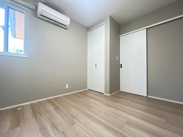 寒田南町二丁目　中古の洋室|淡いグレーの壁と木目調のフローリングが落ち着いた雰囲気を作る洋室です。自然光が差し込み、エアコン完備で快適に過ごせます！