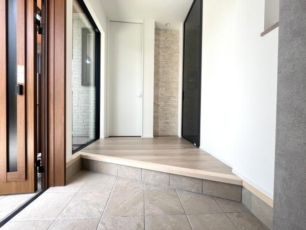 寒田南町二丁目　中古の玄関|ドアは木製で温かみがあり家に帰るたびに落ち着いた雰囲気を感じさせてくれます。床はタイルとフローリングの組み合わせで土間部分はタイル張り上がる部分はフローリングが使われてデザインにメリハリがあります！