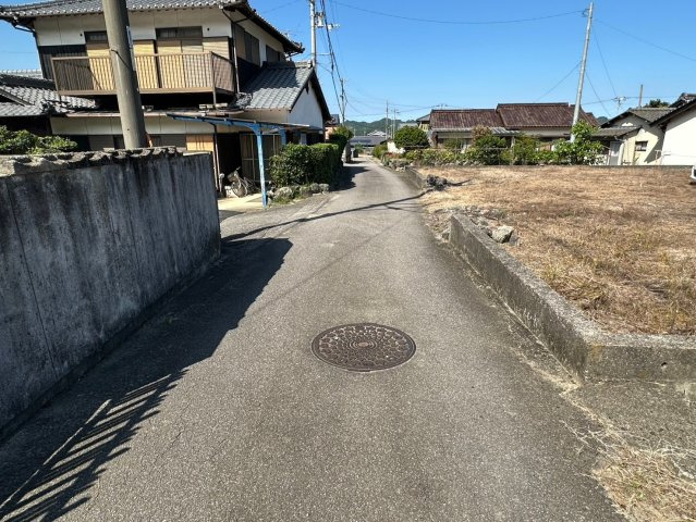 大生院 栗林　売土地の前面道路含む現地写真|西側接道を北向きに撮影。間口は約17メートルあり、車の出し入れもスムーズで、毎朝の通勤がストレスなく行えます。交通量も少なく、お子様の飛び出しにも配慮しやすい安全な環境が目の前に広がります。