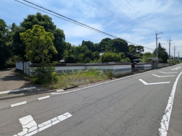 中古戸建　中里見町井ノ下の前面道路含む現地写真|緑の木々と風格ある塀に囲まれた邸宅。前面道路も幅広く整っており、落ち着いた環境で生活いただけます