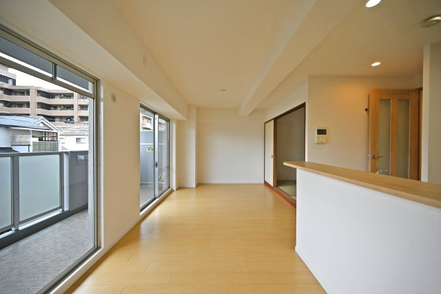 アドリーム伊丹北野の居間・リビング|ダイニングからリビングに向かって撮影した内観写真です。奥正面側にテレビボードを置く配置関係で、対面式キッチンでもあるため調理中もご家族の顔が見渡せるコミュニケーションリビングです。