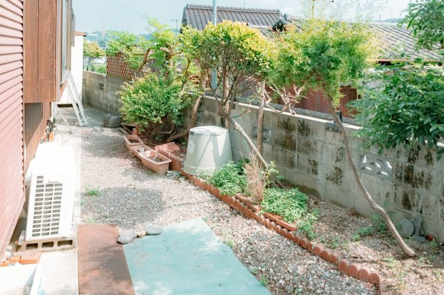 新居浜市東田2丁目　中古戸建の庭|前面道路の幅員があり、駐車時のストレスが少ないのも嬉しいポイント！お庭のスペースにはガーデニング用品を収納するベンチを置いて、趣味の時間を楽しむ。落ち着いた住宅街で、家族の時間を大切に守る一軒家