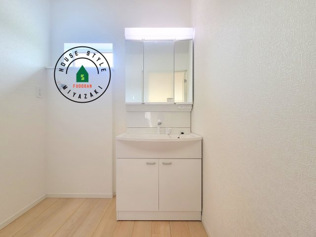 東諸県郡国富町本庄第3-2棟（1号棟）の独立洗面台|毎日使うものだから清潔な空間を保ちたい水回り。洗面にはそんな願いを解消させてくれる収納アイデアが満載です。三面鏡の裏側にはキャビネットが現れ小物から背の高い物まで収納できます。