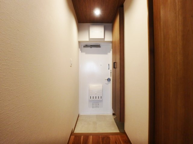 甲子園住宅の玄関|玄関横には大容量のシューズボックスを新設しています。
天井のアクセントクロスがリゾートホテルの雰囲気を演出しています。