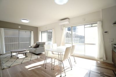 【居間・リビング】 | 【リノベ済】エメラルドマンション安古市 | 【約14帖LDK】
大きな開口部からやわらかな光が差し込み、
ダイニングとリビングがゆるやかにつながる心地よい空間。
キッチンとも視線が通り、日常の動きが自然に整う、
明るく開放感のある住まいです