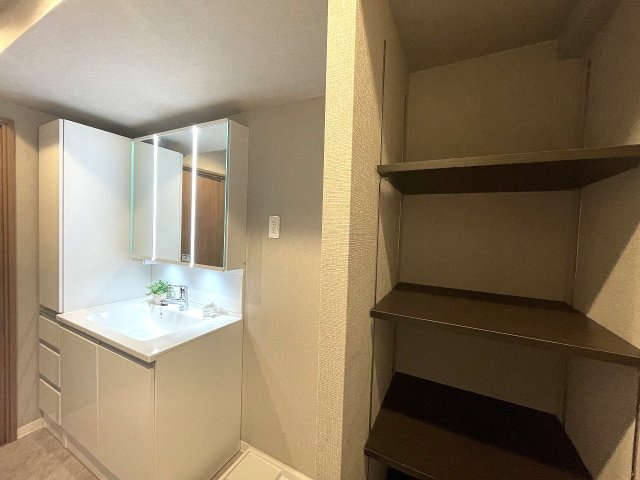 パルハイツ呉中央5丁目の脱衣所|可動式の収納棚が配置され、洗面化粧台にも小物を整理できる収納が設置されており、整理整頓の手助けになります。