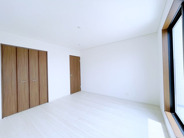 熊谷市上之　AiTOWN　全2邸の洋室|茶色のクローゼットと白基調の洋室に差し込む自然光が温かみのある柔らかな空間を演出！