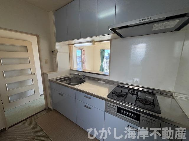 ライオンズガーデン茅ヶ崎一番館のキッチン|窓からの光が届く明るいシステムキッチン。三口コンロやグリルを備え、日々の調理がしやすいレイアウトです。