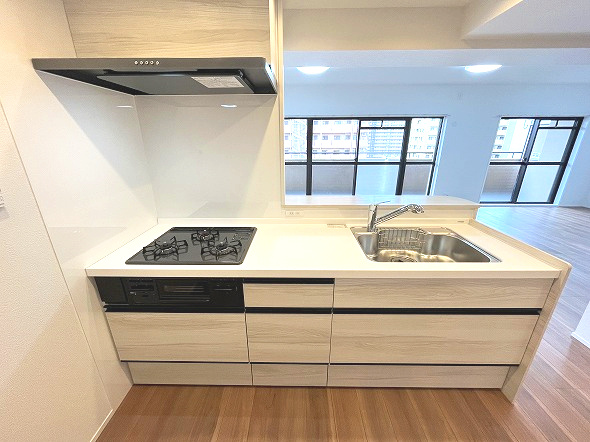 スペリア名南コンフォートのキッチン|木目調のキャビネットと白いカウンタートップが美しい機能的なシステムキッチンです。広々としたシンクと調理スペースでお料理の時間が快適になります。