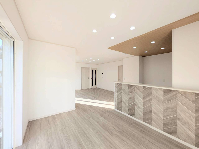 【4号棟:LDK】木目調でグレージュ色のフローリングとグレイッシュカラーでヘリンボーン柄のキッチンカウンターがデザイン性と温もりを感じさせるおしゃれなLDKです。