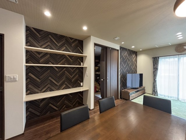 野田市柳沢　中古戸建　令和3年築の居間・リビング|リビングにはスペースを活用したカウンターと棚があります！カウンターは勉強やデスクワークに活躍します！上には2段の棚があり、収納スペースとしても活用できます！