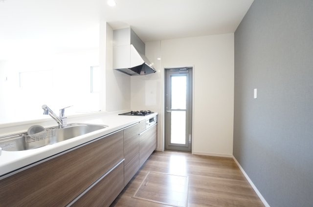 リーブルガーデン美浜町奥田西卯起　1号棟のキッチン|グレーのアクセントクロスが落ち着いた雰囲気のキッチンは、使いやすく対面式カウンター付きで
家族の様子がわかります