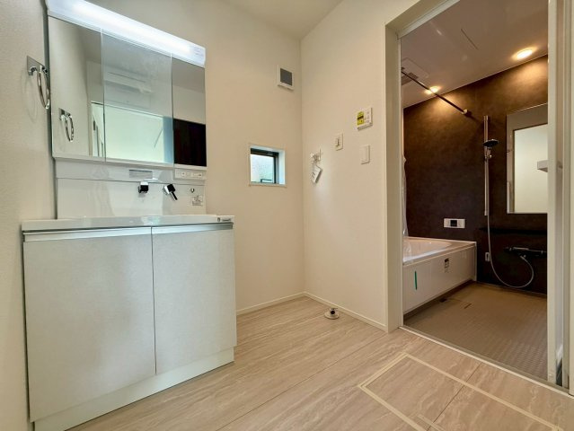 香美市土佐山田町宝町2期5棟 2号棟の独立洗面台|三面鏡収納の洗面化粧台は清潔感と機能性を両立。ゆとりのある洗面脱衣室で、家事も身支度もスムーズです。