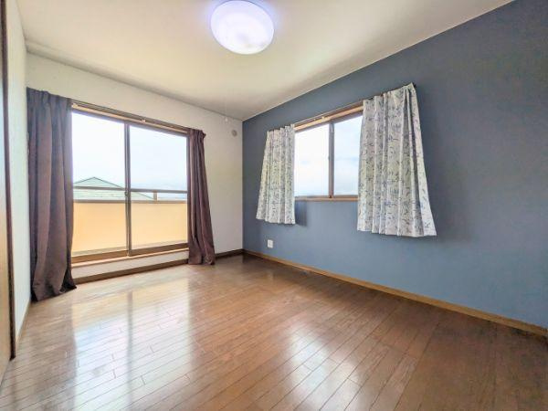 けやき台二丁目　中古の洋室|ナチュラルな木目調のフローリングが特徴の洋室です。二面採光で室内が明るい印象です。壁のアクセントカラーが落ち着きを感じさせます。バルコニーに面した大きな窓が開放感を演出します。
