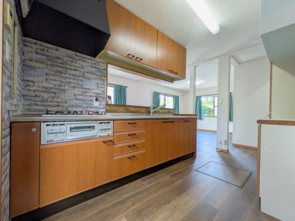 けやき台二丁目　中古のキッチン|木目調のキッチンが温かみを感じさせます。広々としたカウンターで作業がしやすいです。収納スペースも豊富で整理整頓がしやすい仕様です。石目調の壁面が空間にアクセントを加えています。