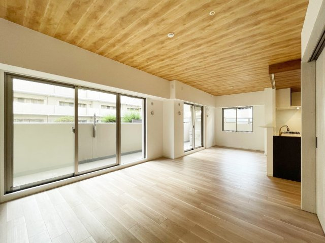 アルス西宮ルシーディアの居間・リビング|南、西の2面採光で明るいリビングです。天井は木目のクロス貼りで、温かみのある雰囲気を演出しています。柱の出っ張りがないアウトポール設計、段差の少ないフルフラット設計のマンションです。