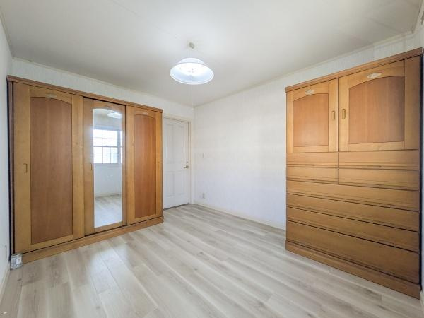 王ノ瀬一丁目　中古の洋室|明るい床材が特徴的な洋室です。収納力のある大型クローゼットとチェストが設置されています。清潔感のある白い壁が空間をより広く感じさせます。天井照明がしっかりと部屋全体を照らしています。