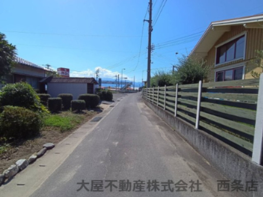 西条市小松町新屋敷甲2279-1　売土地の周辺|北側幅員約4ｍの道路に15.5ｍ接しており、視界を遮るものがなく開放的な雰囲気です。前面道路の交通量も落ち着いているため、落ち着いた環境で駐車もスムーズに行え、安全に帰宅できる毎日が待っています。