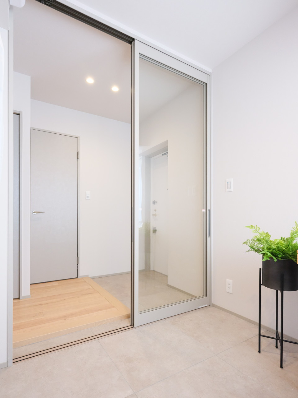 東京八重洲アムフラットの洋室|住まいの顔となる玄関スペースには洋室2の窓からの陽光が降り注ぎます。洋室2と同様のフラットタイルを採用しシームレスな空間へと演出します