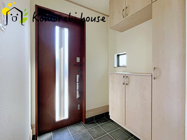 さいたま市北区吉野町2丁目192番11　新築一戸建て　Eの玄関|窓から明るい陽が差し込む玄関ドア。
この字型のシューズボックスの真ん中にはご家族の写真を置いてお出迎え♪