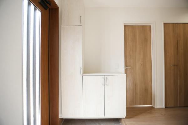 大字森町4期1号棟の玄関|明るい玄関が印象的です。収納スペースが豊富に設けられています。全体的に落ち着いた配色で統一されています。木目調のドアが温かみを感じさせます。