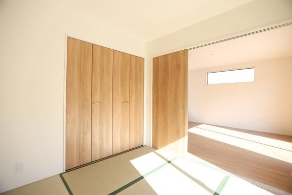 大字森町4期1号棟の和室|和室と洋室の間には引き戸が設置され空間を仕切ることができます。ナチュラルな木目の建具が室内に温もりを演出しています。採光窓からはやさしい光が差し込み明るい雰囲気です。収納スペースも備わっています。