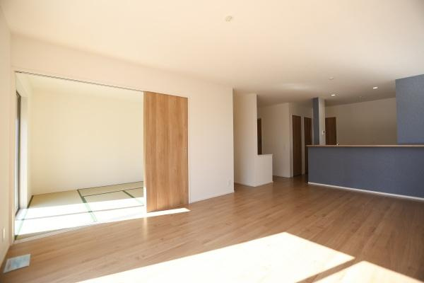 大字森町4期1号棟の居間・リビング|広々とした空間が広がるリビングです。明るい日差しがしっかりと差し込みます。隣接した和室との一体感も魅力です。落ち着いた色合いのフローリングが特徴的です。開放感のある間取りとなっています。