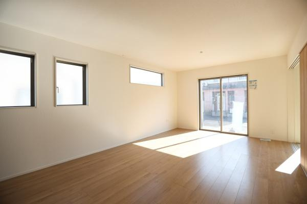 大字森町4期1号棟の居間・リビング|窓が多く自然光がたっぷりと入るリビングです。床材は落ち着いた色合いで室内が広く感じられます。シンプルなデザインが特徴的でさまざまなインテリアに合わせやすい空間です。スライドドアからの出入りも便利です。