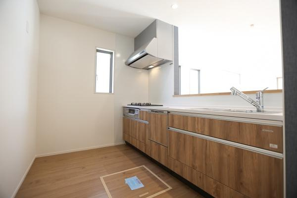 大字森町4期1号棟のキッチン|木目調のデザインが印象的なキッチンです。窓からの採光があるため明るい印象です。作業スペースが広く日々のお料理も快適に進められます。収納が豊富に確保されています。清掃しやすいシンプルな空間です。