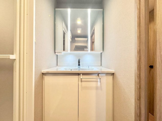 【独立洗面台】 | パデシオン桃山南 | 洗面化粧台は新調しています。三面鏡タイプの洗面台で、鏡裏にも歯ブラシなどの小物が収納できます。備付けの照明が手元を明るく照らしてくれます。