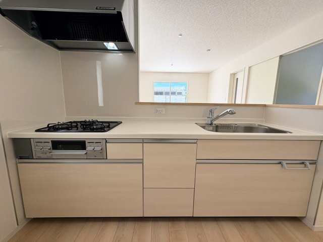 クレイドルガーデン糸満市宇江城 第2・2号棟のキッチン|レンジフード＆ガスコンロ３口＆浄水器／キッチンからダイニングの眺め