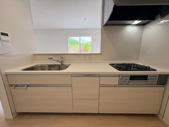 クレイドルガーデン糸満市宇江城 第2・3号棟のキッチン|レンジフード＆ガスコンロ３口＆浄水器／キッチンからダイニングの眺め
