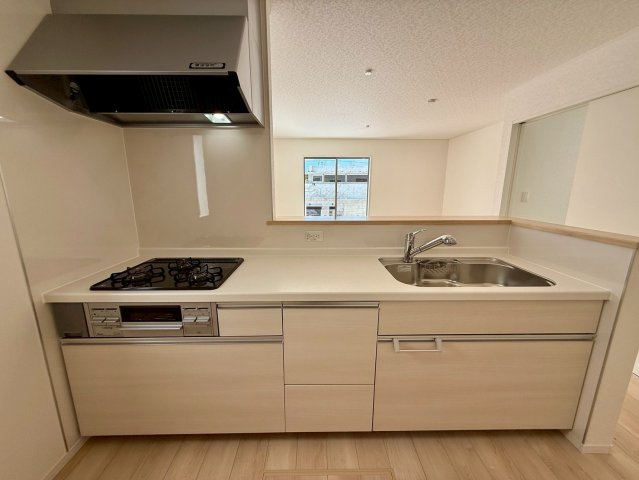 クレイドルガーデン糸満市宇江城 第2・4号棟のキッチン|レンジフード＆ガスコンロ３口＆浄水器／キッチンからダイニングの眺め