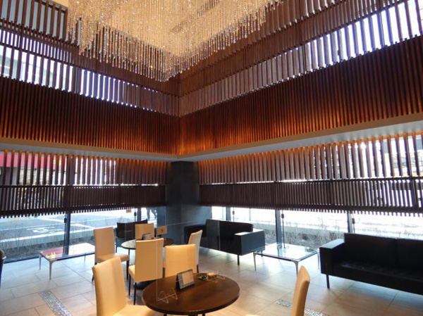 【エントランス】 | 【エントランスホール】二層吹抜。ダイナミックな木製ルーパーが温もりと落ち着きを演出します。