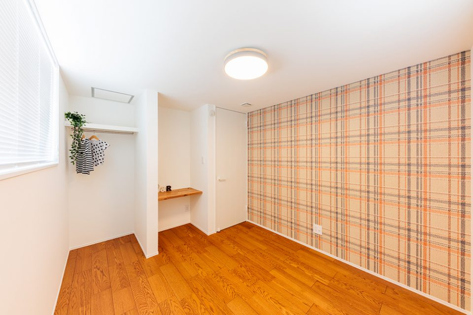 南国市大埇甲　中古一戸建ての洋室|チェック柄のアクセントクロスが可愛い子ども部屋。オープンクローゼットとデスク付きで、収納も学習スペースも確保されています